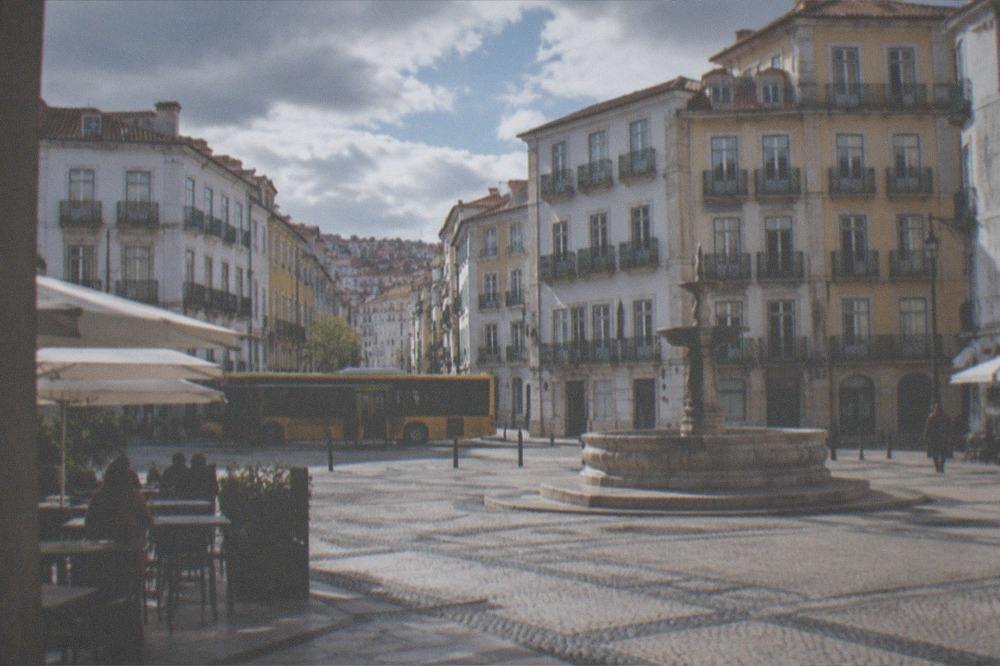 A yellow city bus stopped at a street stop in a Portuguese city centre