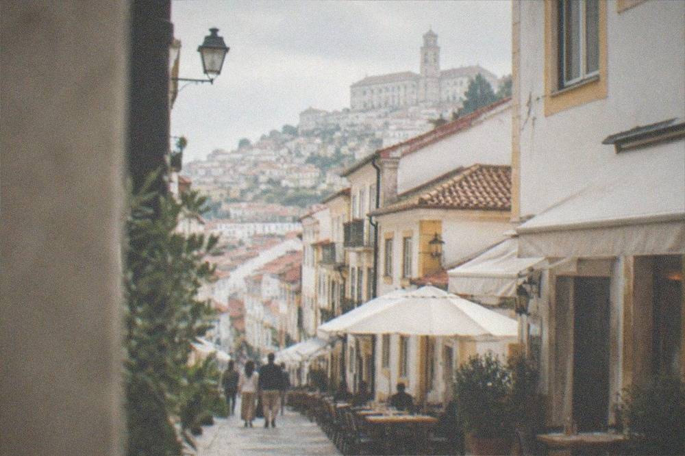 A narrow pedestrian street in central Coimbra lined with small restaurants and café awnings