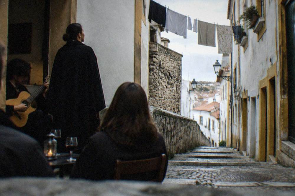 A fado singer in a student's black cape performing to a small room in Coimbra