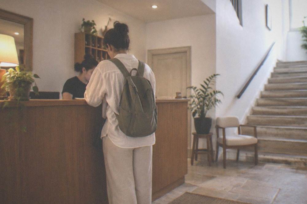 Guest receiving a room key at a small hotel reception desk