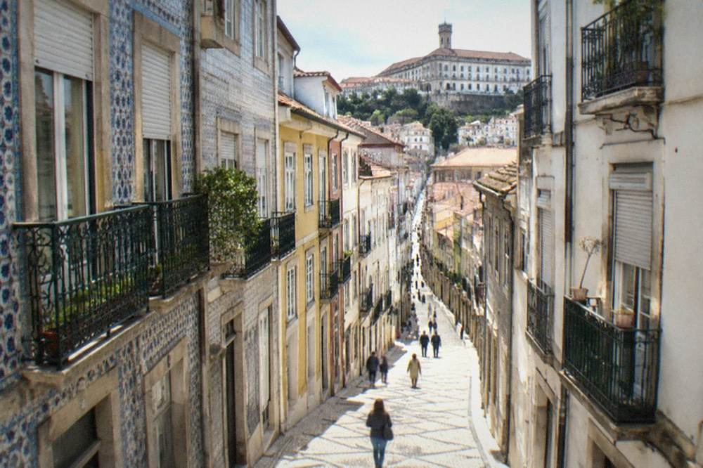 A steep cobbled lane in Coimbra's old town climbing toward the university buildings above