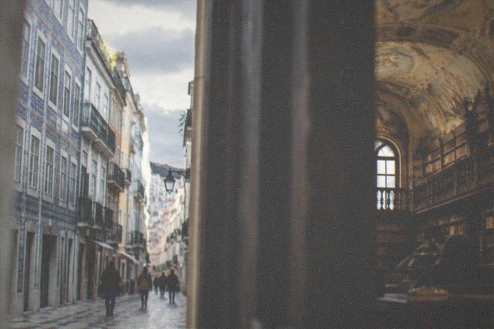 The baroque interior of a library with tall wooden bookshelves and painted ceilings