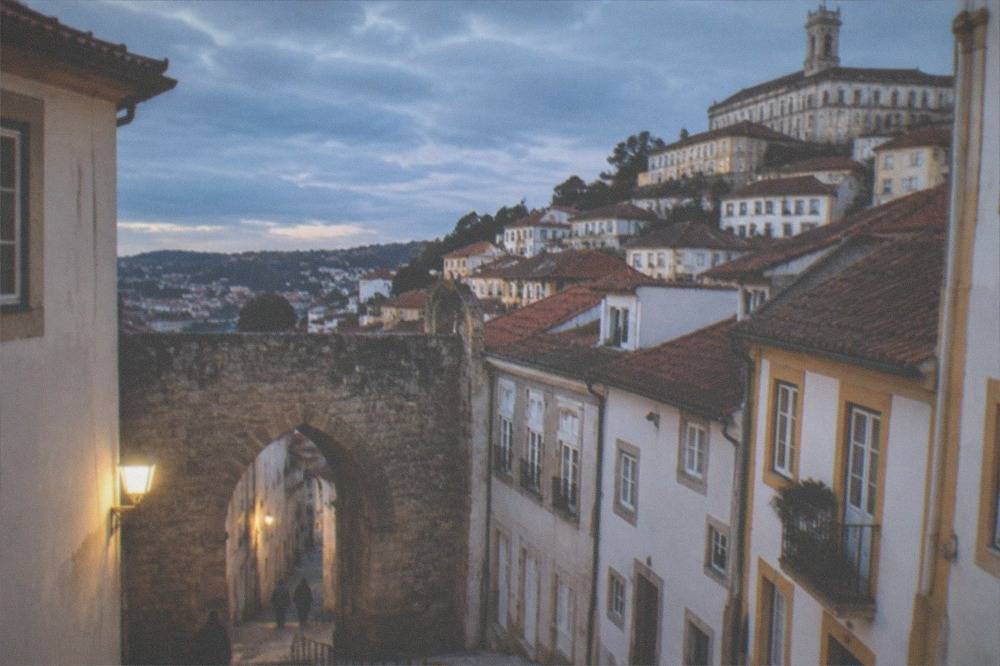 A stone gate and steep cobbled lane leading up toward the university buildings in Coimbra.