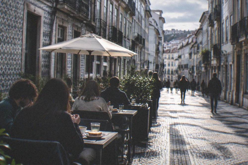 A café terrace with students eating soup and toast at small tables