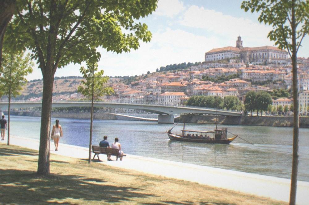 A traditional wooden boat on the Mondego river below Coimbra's old bridge in bright summer sunshine