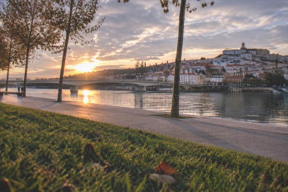 Sunset colours over the Mondego river and Coimbra's hillside cityscape