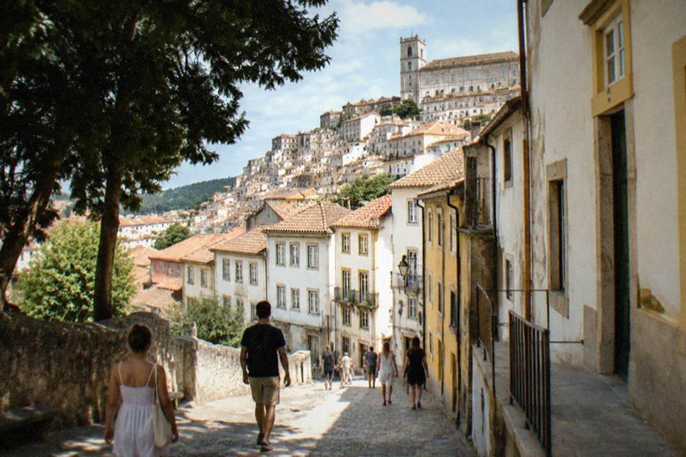Visitors walking through the old town of Coimbra in warm late summer light