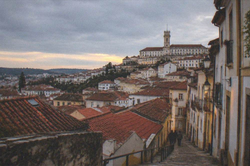 An evening view over the terracotta rooftops of Coimbra with the university tower in the distance