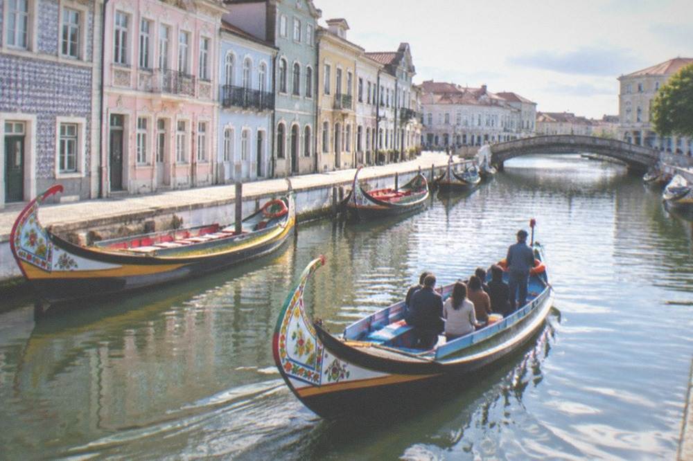 A flat-bottomed boat gliding down a narrow town canal lined with tiled buildings