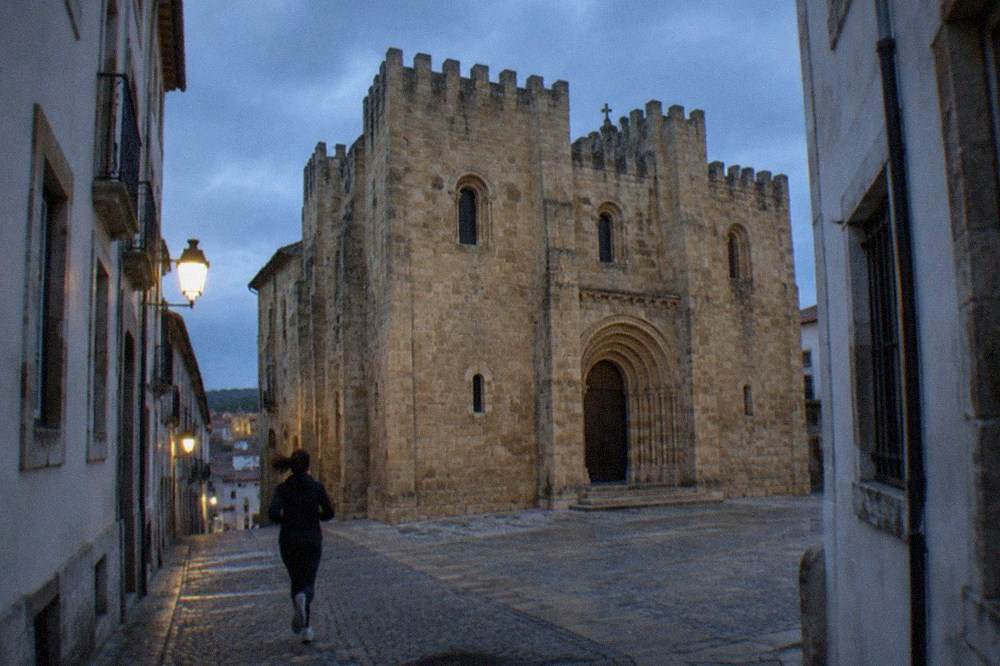The Romanesque exterior of the Se Velha old cathedral in Coimbra seen from a narrow street