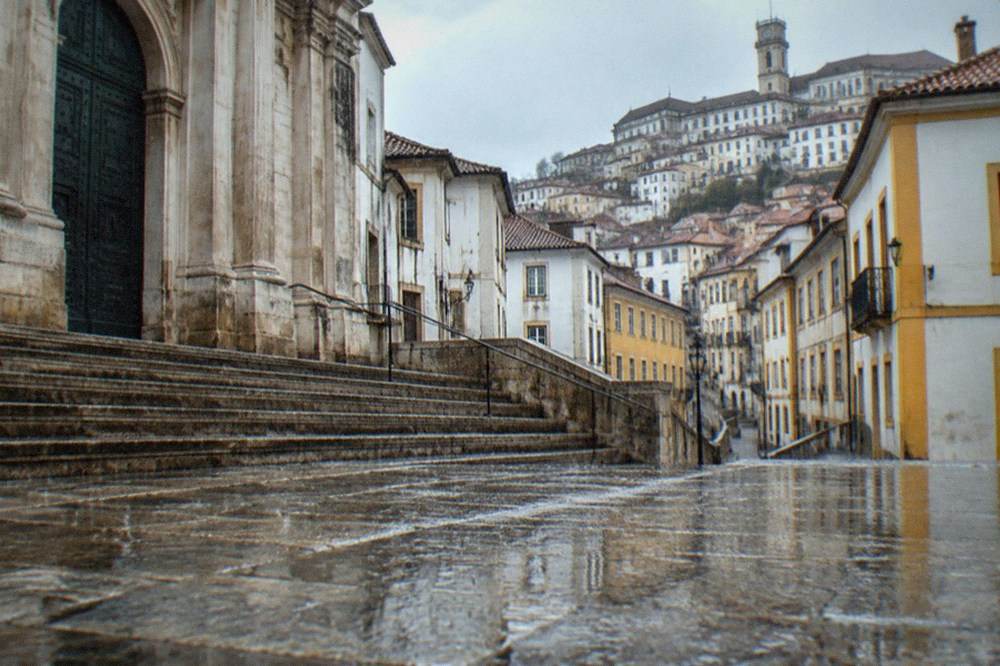 Closed museum entrance in Coimbra with rain falling on empty stone steps