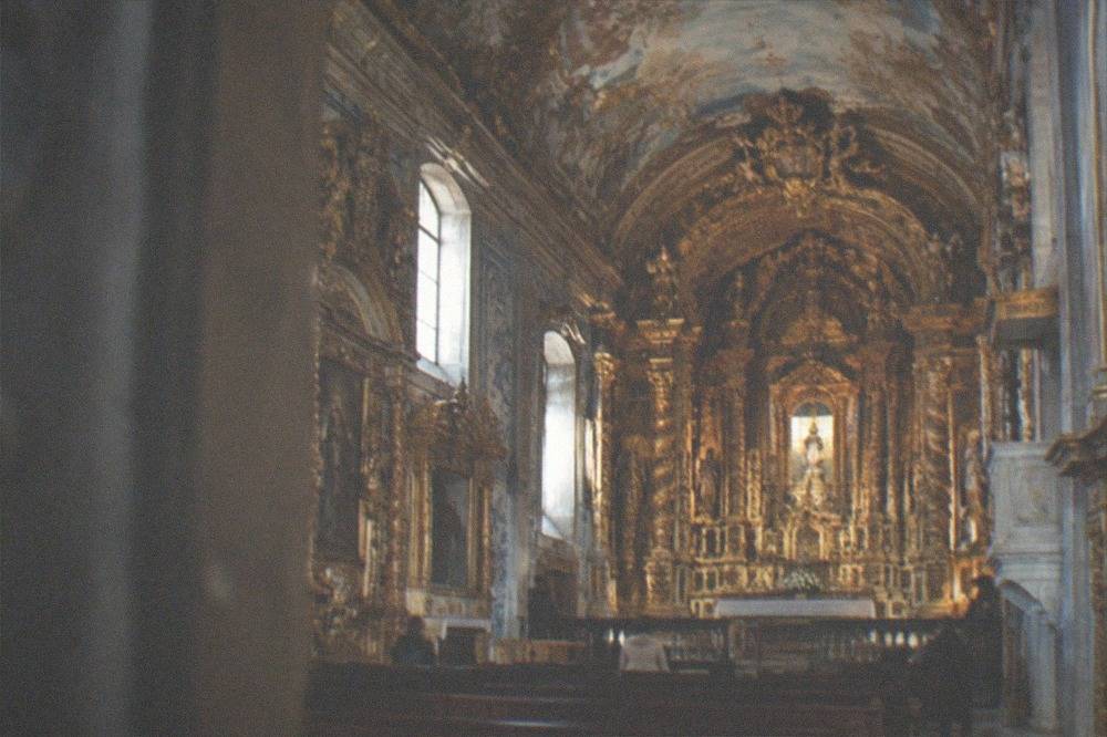 Ornate baroque chapel interior with gilded woodwork and painted ceiling in Coimbra