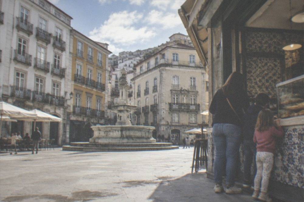 A parent and two children eating pastries at the counter of an old tiled cafe in the city centre