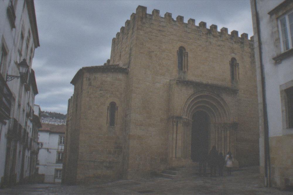 A family standing outside the carved Romanesque doorway of an old cathedral in the evening light